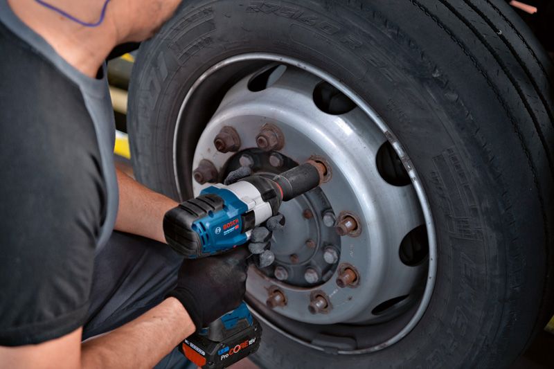 GDS 18V-1050 H Một người mặc thiết bị an toàn sử dụng cờ lê tác động để siết chặt bu lông trên bánh xe tải.