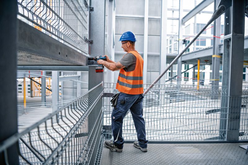 Người mặc thiết bị an toàn sử dụng cờ lê tác động vào dầm thép tại công trường xây dựng.