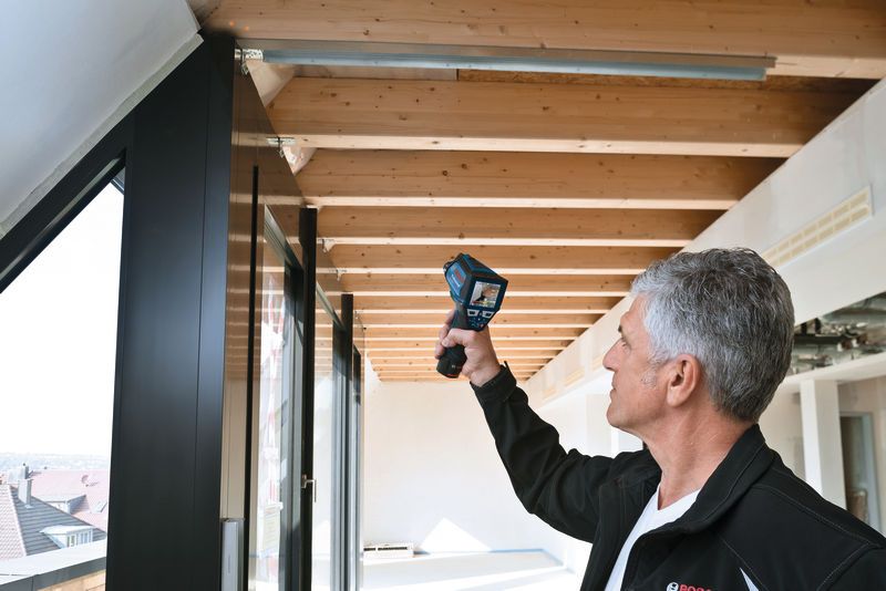 Một người đang quét dầm trần bằng thiết bị kiểm tra cầm tay.