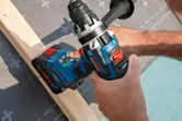 Một người sử dụng máy khoan không dây để khoan một thanh gỗ.