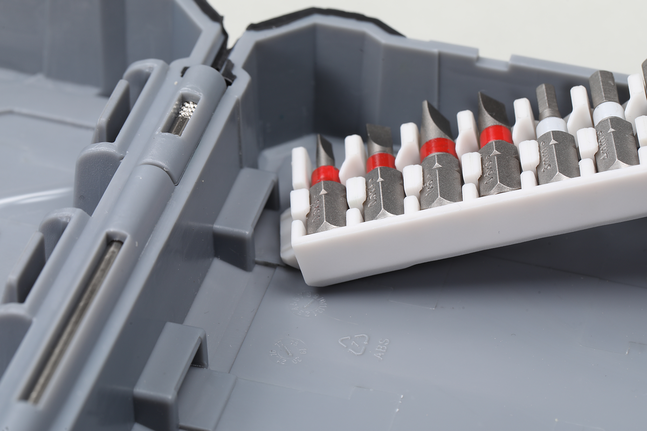 Các loại đầu vít khác nhau được sắp xếp gọn gàng trong một hộp nhựa bên trong một hộp dụng cụ màu xám.