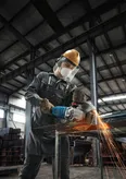 Một người mặc đồ bảo hộ sẽ cắt kim loại bằng máy mài góc, tạo ra tia lửa.