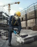 Một người mặc đồ bảo hộ đang cắt khối bê tông tại công trường xây dựng.