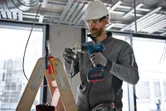 Một người mặc thiết bị an toàn sử dụng súng nhiệt không dây trên hệ thống dây điện.