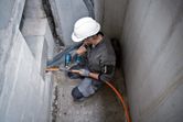 Một người mặc thiết bị an toàn đang sử dụng súng nhiệt không dây để làm việc trên một sợi cáp màu cam.