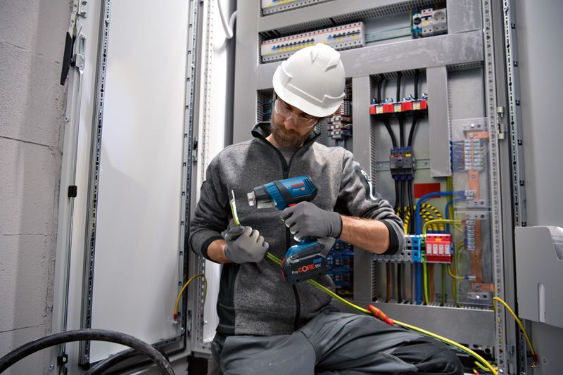 Một người mặc thiết bị an toàn sử dụng súng nhiệt không dây trên hệ thống dây điện.