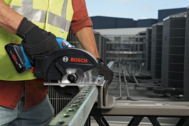 GKM 18V-50 Một người mặc đồ bảo hộ đang cắt một thanh kim loại bằng máy cưa tròn không dây.