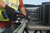 Một người mặc đồ bảo hộ đang cắt một thanh kim loại bằng máy cưa tròn không dây.