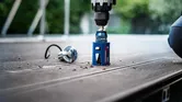 Dụng cụ điện khoan lỗ chính xác trên tấm ván gỗ ngoài trời.
