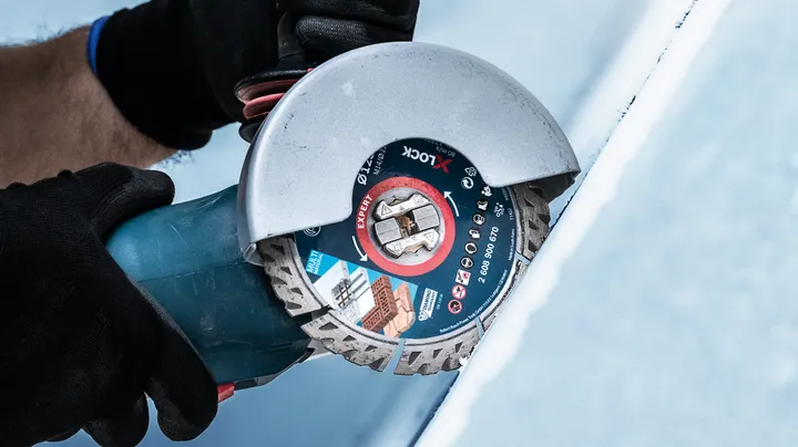 Object #200360653: 2793282_app_web_01 Một người mặc đồ bảo hộ đang cắt gạch bằng máy mài góc.