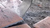 Đục phá gạch lát sàn bằng gốm, tạo ra bụi và mảnh vụn.