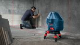 Một người đang lắp gạch ốp tường bằng công cụ cân bằng laser để căn chỉnh.
