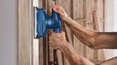 Người ta chà nhám bề mặt gỗ bằng máy chà nhám quỹ đạo.