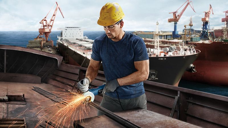 Công nhân mài kim loại tại xưởng đóng tàu.