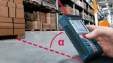 Một người sử dụng máy đo laser để kiểm tra khoảng cách trên sàn nhà kho.