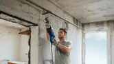 Một người mặc thiết bị an toàn đang sử dụng cưa lọng để cắt ống kim loại trong nhà.