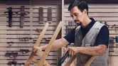 Một người đang cố định các miếng gỗ bằng tua vít không dây trong xưởng.