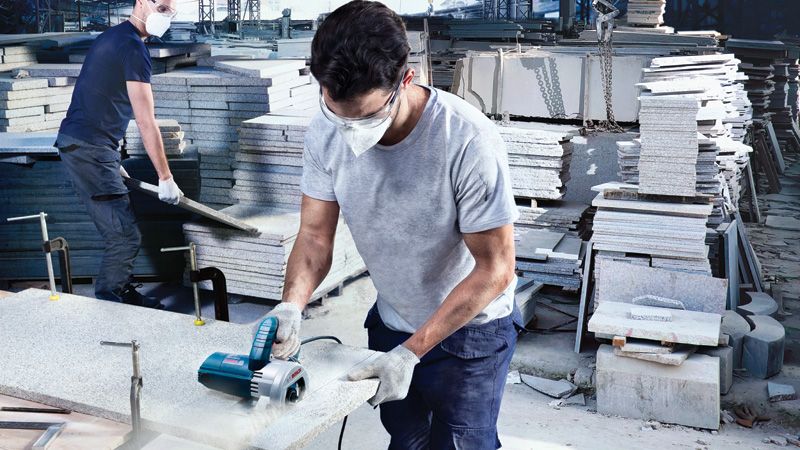 Máy cắt gạch kim cương Bosch GDC 140 đang được sử dụng trên tấm đá.
