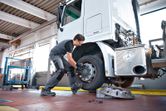 Một người mặc thiết bị an toàn sử dụng cờ lê tác động để tháo bánh xe tải.