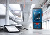 Máy đo laser và máy tính bảng hiển thị số đo trên bề mặt bê tông tại công trường xây dựng.