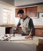 Một người đeo thiết bị an toàn đang khoan vào tấm ván gỗ trên quầy bếp.