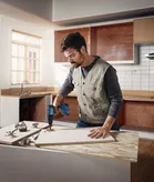 Người đeo thiết bị an toàn đang khoan vào tấm ván gỗ trong khu vực bếp.