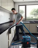 Một người mặc đồ bảo hộ đang hút bụi nhà bếp bằng máy hút bụi ướt và khô.