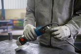 Một người mặc đồ bảo hộ đang chuẩn bị cắm điện cho máy mài góc.