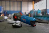 Máy mài góc điện có gắn bộ lọc bụi đặt trên bàn làm việc trong xưởng.