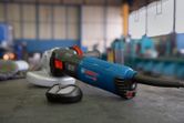 Máy mài góc điện có gắn bộ lọc bụi đặt trên bàn làm việc trong xưởng.