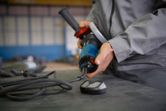 Người đeo thiết bị an toàn đang kết nối dụng cụ điện trên bàn làm việc.
