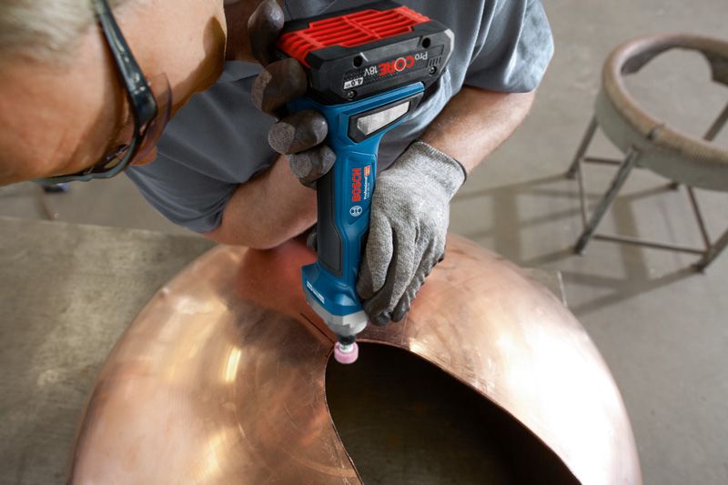 Một người mặc thiết bị an toàn đang mài mép của một mái vòm kim loại lớn.