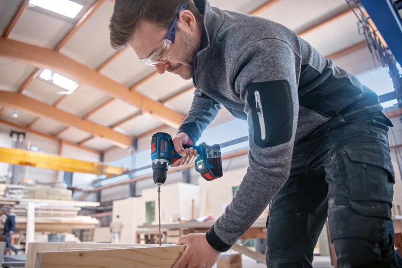 GSR 18V-90 C Một người đeo thiết bị an toàn đang khoan gỗ bằng dụng cụ điện không dây.