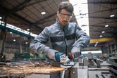 Một người mặc đồ bảo hộ đang mài kim loại, tạo ra tia lửa trong một xưởng công nghiệp.