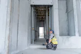 Một người mặc thiết bị an toàn sử dụng máy đo laser để kiểm tra khoảng cách trong một kết cấu bê tông.