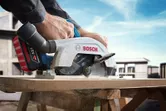 Một người đang sử dụng máy cưa tròn không dây để cắt gỗ tại một công trường xây dựng.