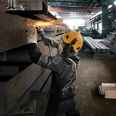 Một người mặc thiết bị an toàn mài một thanh kim loại, tạo ra tia lửa sáng.