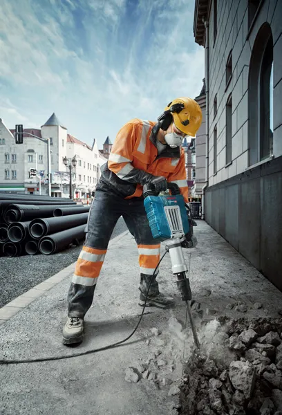 GSH 14 C Một người mặc đồ bảo hộ đang phá vỡ vỉa hè bằng cầu dao điện trên đường phố thành phố.