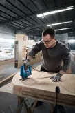 Người đeo thiết bị an toàn sử dụng máy cưa lọng để cắt các hình cong trên ván ép.