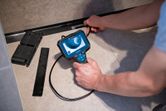 Người vận hành camera kiểm tra để kiểm tra bên trong một không gian sàn hẹp.