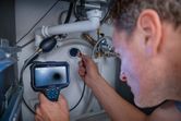 Một người đang kiểm tra hệ thống ống nước dưới bồn rửa bằng camera kiểm tra.