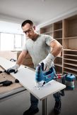Một người mặc đồ bảo hộ đang cắt gỗ bằng máy cưa lọng trong xưởng.