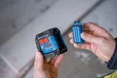 Một người cầm một máy cân bằng laser và một bộ pin.