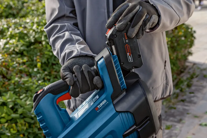 GBL 18V-750 Một người đeo thiết bị an toàn đang lắp pin vào máy thổi lá không dây.