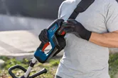 Một người đeo thiết bị an toàn đang gắn pin vào máy cắt cỏ không dây.
