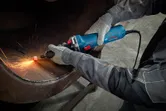 Một người mặc đồ bảo hộ sẽ sử dụng máy mài thẳng để mài kim loại, tạo ra tia lửa.