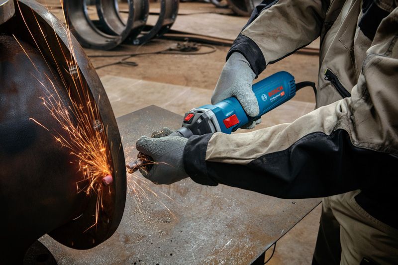 Một người mặc đồ bảo hộ sẽ mài kim loại, tạo ra tia lửa sáng.