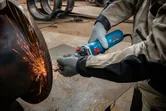 Một người mặc đồ bảo hộ sẽ mài kim loại, tạo ra tia lửa sáng.