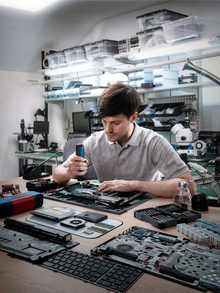 Người đang lắp ráp các thiết bị điện tử bằng tua vít không dây trong xưởng.