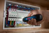 Người sử dụng tua vít không dây để siết chặt ốc vít trên bảng điện.